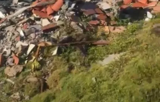 Restos de obra são jogados entre pedras de contenção na praia de Jauá