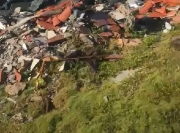 Restos de obra são jogados entre pedras de contenção na praia de Jauá