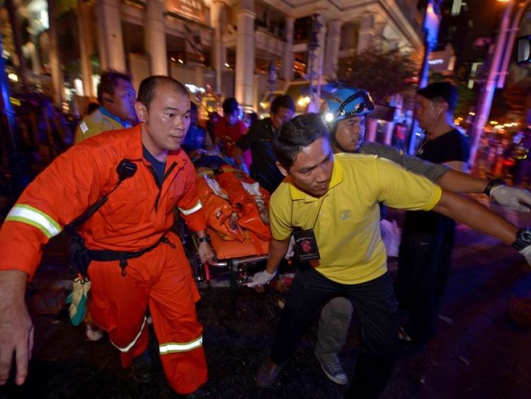 Equipe de resgate socorre um ferido no local onde explodiu uma bomba no centro de Bangcoc, na Tailândia (Foto: Pornchai Kittiwongsakul/AFP)