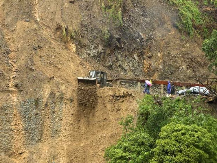 Operários trabalham para desobstruir estrada fechada após deslizamento de terra nas Filipinas (Foto: Harley Palangchao / Reuters)